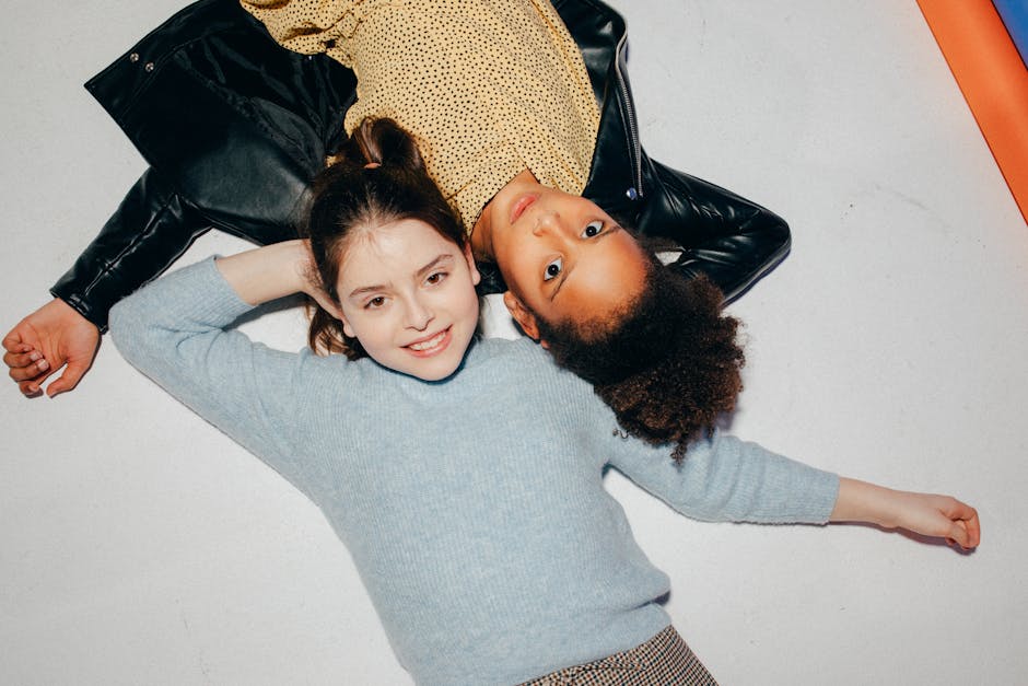 Two diverse girls lying on the floor, smiling and enjoying each other's company.