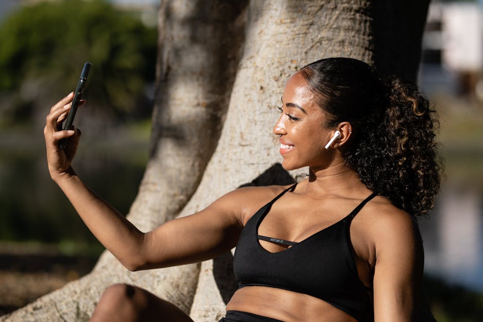 A woman in activewear taking a selfie in a natural outdoor setting, smiling.