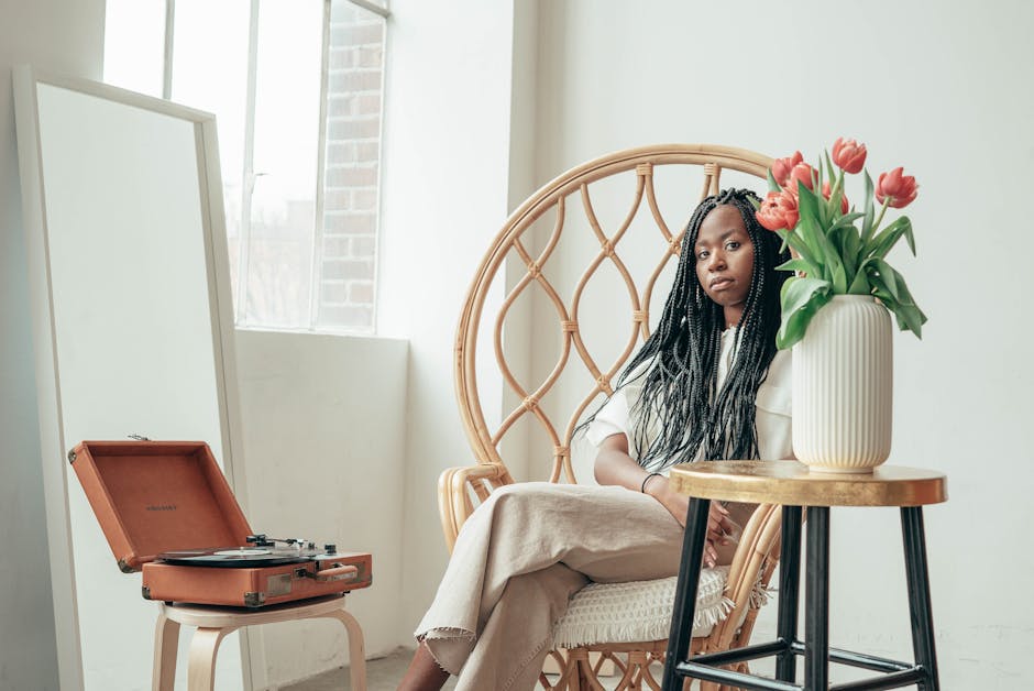 African woman enjoying a tranquil morning with vinyl music and tulips, indoors, creating a cozy and peaceful atmosphere.